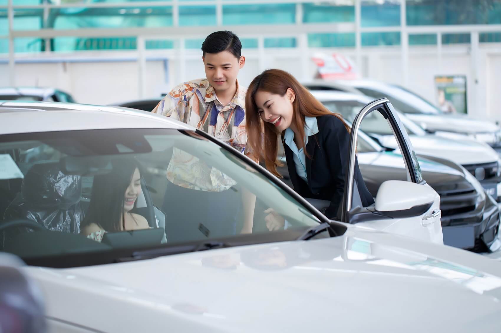 Customers looking at new vehicle in showroom with sales consultant